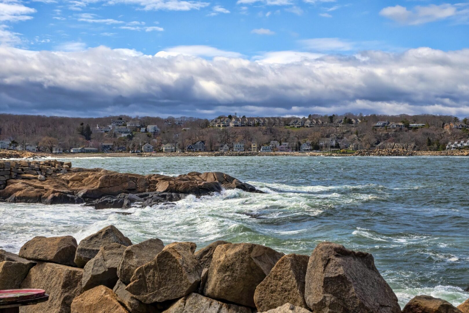 A body of water with rocks and waves in the foreground.